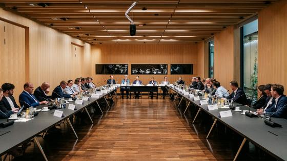 Gruppenfoto, die Teilnehmer und Teilnehmerinnen sitzen in U-Form an einem Besprechungstisch 