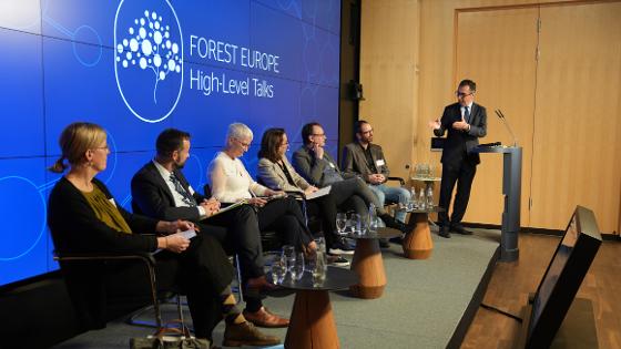 Bundesminister Cem Özdemir am Rednerpult hinter ihm die Podiumsteilnehmer. Rückwand mit dem Schrifzug "Forest Europe High-Level Talks