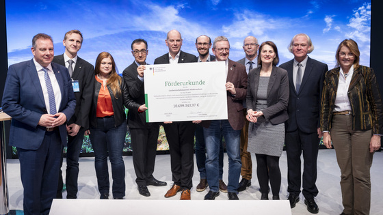 Gruppenfoto auf der Bühne mit dem Förderbescheid