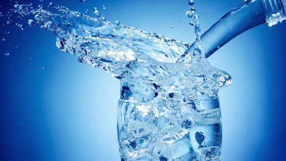 Wasser wird von ein Flasche in ein Glas gegossen Wasser wird von ein Flasche in ein Glas gegossen