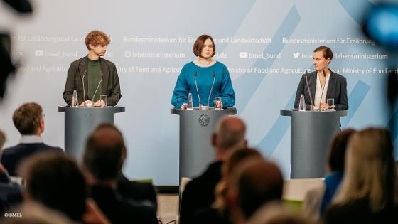 Parlamentarische Staatssekretärin Claudia Müller steht am Pult und hält eine Rede bei einer Pressekonferenz. Neben ihr stehen 2 weitere Personen. Im Hintergrund: eine blaue Rückwand mit BMEL-Aufschrift.