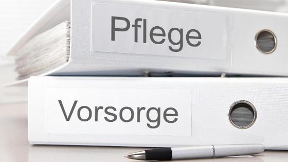  Zwei Ordner mit Aufschrift "Pflege und Vorsorge", davor ein Stift