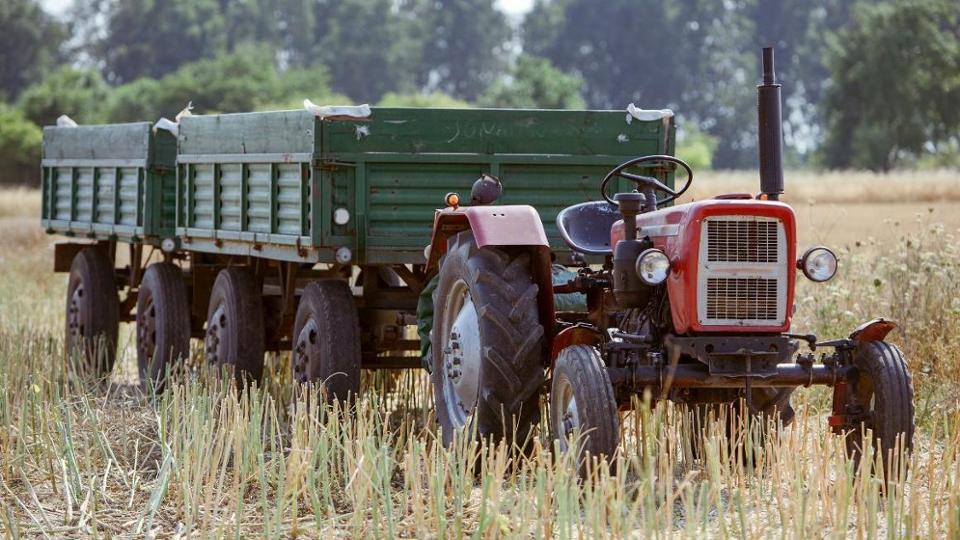 Traktor mit Anhänger auf einem Stoppelfeld