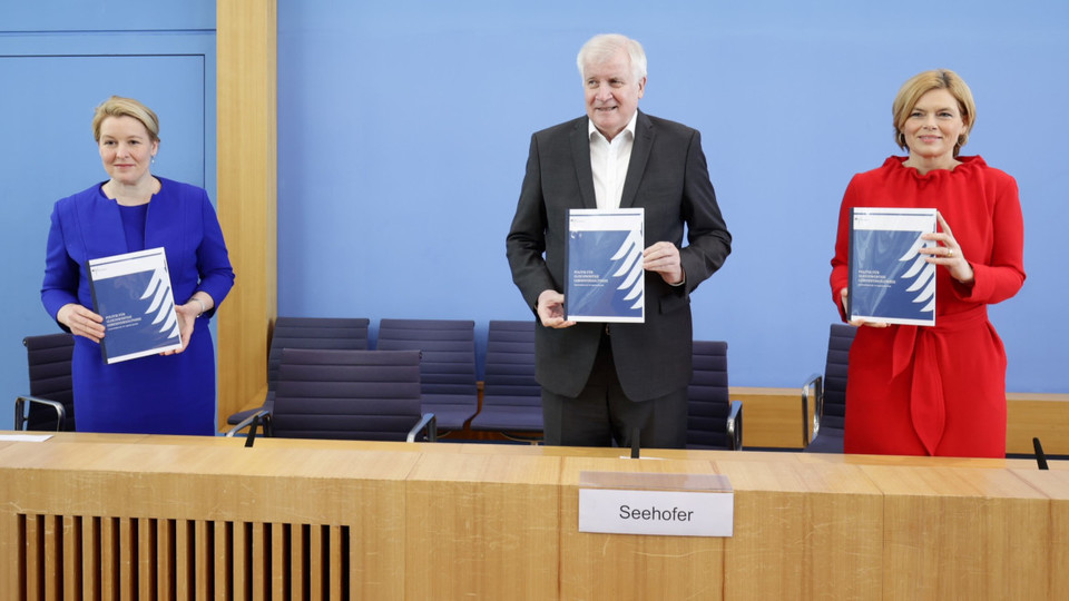 die Bundesminister Klöckner, Seehofer und Giffey im Podium der Bundespressekonferenz mit der Zwischenbilanz in der Hand