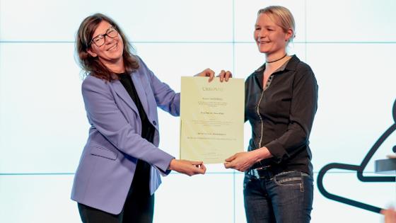 Parlamentarische Staatssekretärin Nick und Frau Prof. Dr. Klein halten die Urkundes des Forschungspreises in die Kamera 