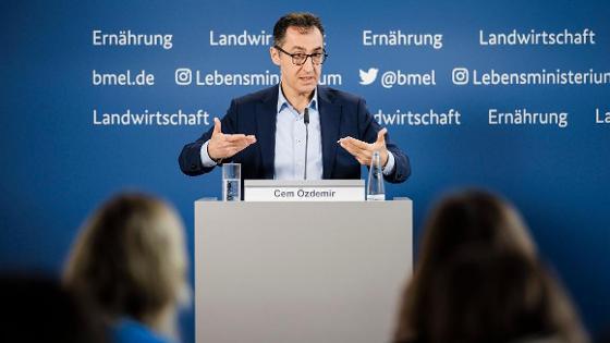 Bundesminister Özdemir steht vor einer BMEL-Pressewand und spricht. Er gestikuliert hinter einem Pult mit Mikrofonen. Im Anschnitt sind Journalisten zu sehen.