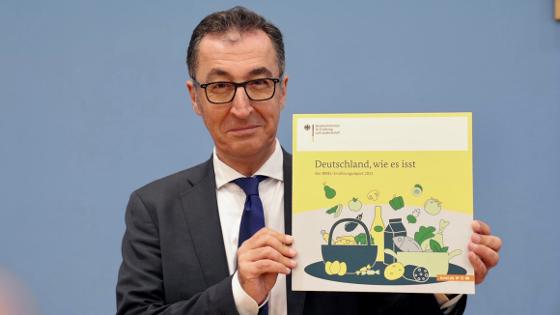 Bundesminister Özdemir hält den neuen Ernährungsreport in die Kamera