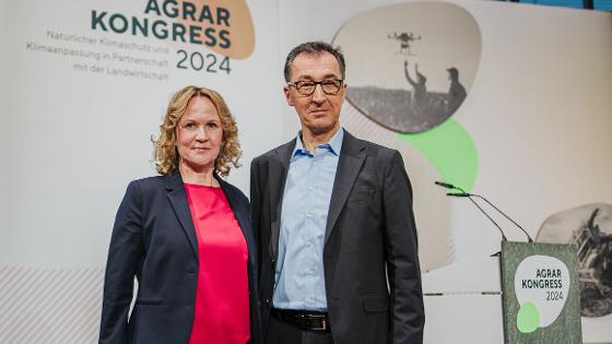 Bundesumweltministerin Steffi Lemke und Bundeslandwirtschaftsminister Cem Özdemir stehen vor der Rückwand des Agrarkongresses 2024 "Natürlicher Klimaschutz und Klimaanpassung in Partnerschaft mit der Landwirtschaft"