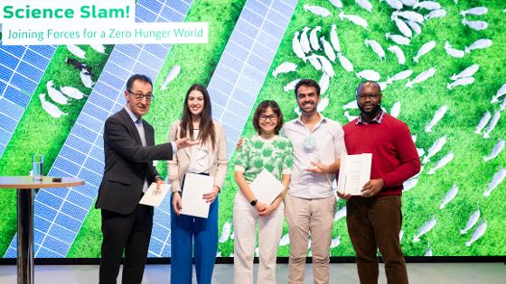 Bundesminister Özdemir mit Teilnehmenden des Science Slam auf der Bühne.