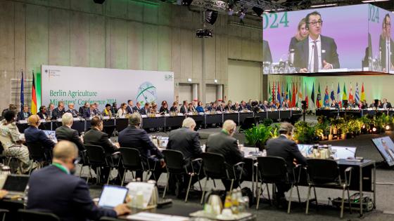 Blick in den Plenarsaal der Agrarministerkonferenz, groß auf Bildschirmen von der Decke Bundesminister Özdemir