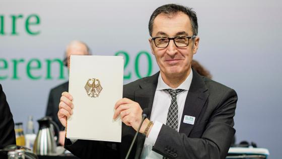 Bundesminister Özdemir hält eine Mappe mit goldenen Bundesadler mit dem Abschlusskommunique in die Kamera