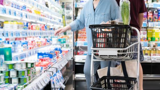 Eine Frau greift in einem Supermarkt nach einem Produkt im Kühlregal.