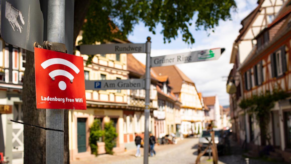 In einem Dorf steht ein Schild mit der Aufschrift "Ladenburg Free Wifi". In einem Dorf steht ein Schild mit der Aufschrift "Ladenburg Free Wifi".