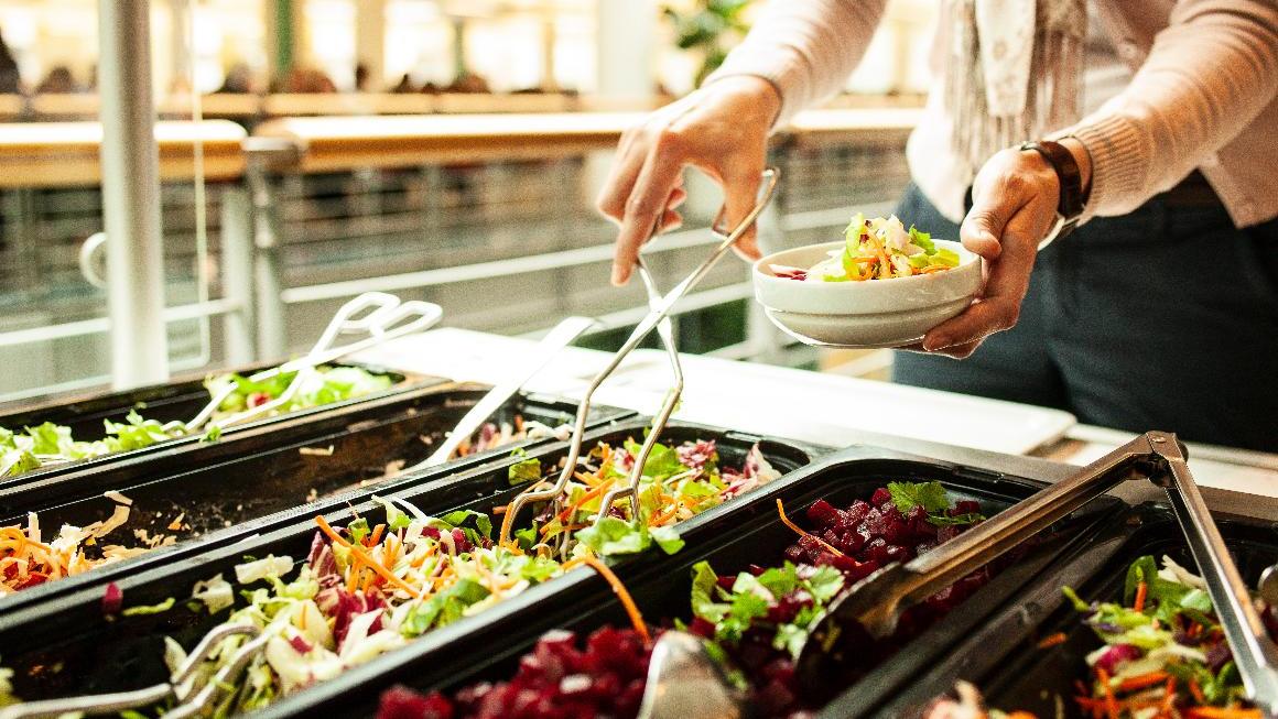 Salatbuffet in einer Kantine, eine Frau bedient sich an einem Salatbuffet Salatbuffet in einer Kantine, eine Frau bedient sich an einem Salatbuffet