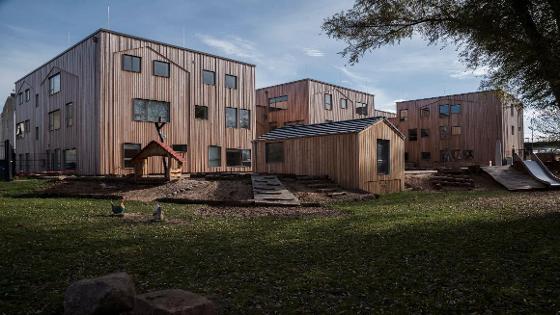 Mehrere Holzgebäude mit Spielplatz davor