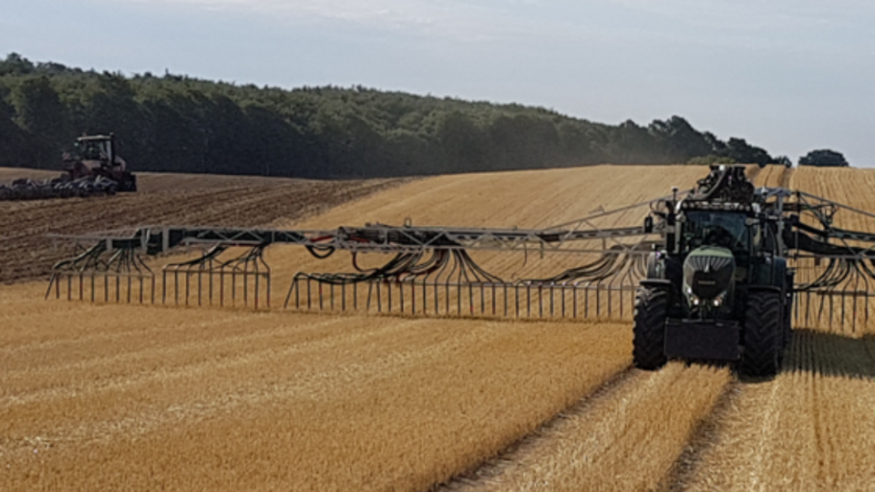 Ein Trecker verteilt Gülle auf einem Feld