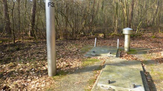 Betonplatten auf dem Waldboden, zwei Rohre ragen aus dem Boden heraus Betonplatten auf dem Waldboden, zwei Rohre ragen aus dem Boden heraus