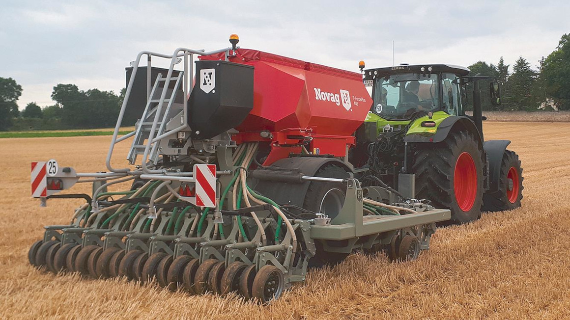 Ein Traktor zieht eine Saatmaschine über den Acker Ein Traktor zieht eine Saatmaschine über den Acker
