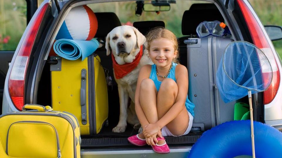 Mädchen mit Hund im Kofferraum
