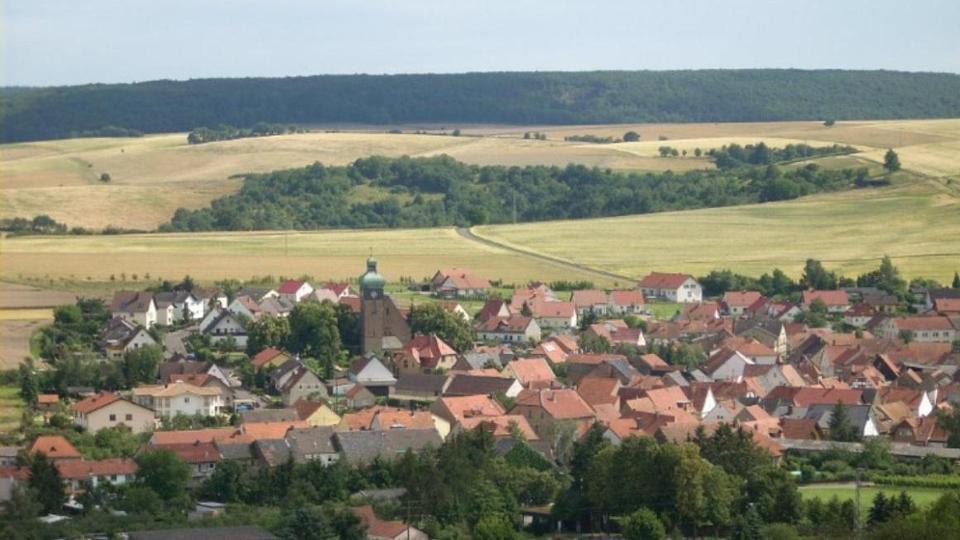 Luftaufnahme des Dorfes mit Kirchturm eingebettet in Felder und Wald Luftaufnahme des Dorfes mit Kirchturm eingebettet in Felder und Wald