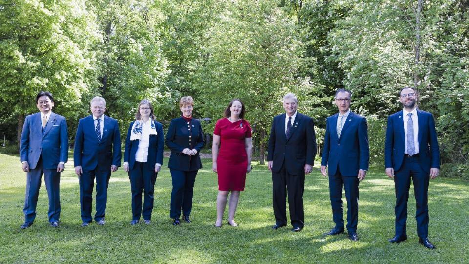 Minister Cem Özdemir, his G7 counterparts and European Commissioner for Agriculture Wojciechowski are standing in front ot trees outside the meeting place in Stuttgart.