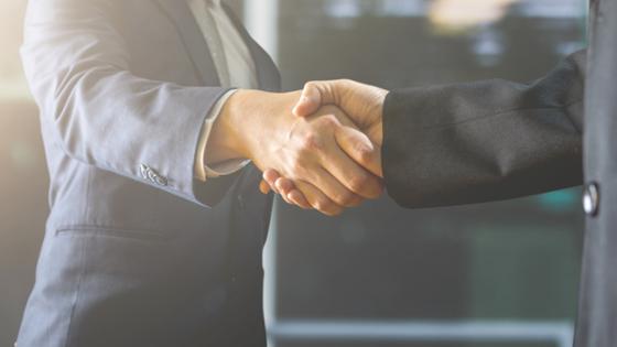 Two gentlemen in business suits shake hands