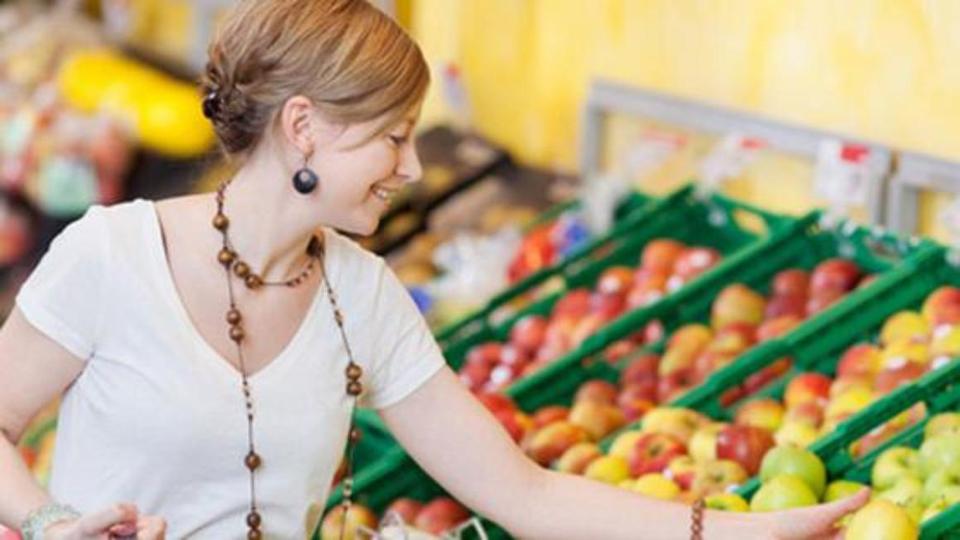 Woman looks at apples in the supermarket