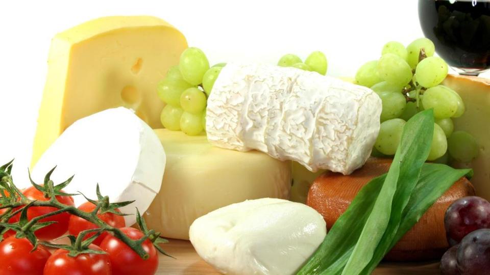 Cheese plate garnished with tomatoes, grapes and a glass of red wine