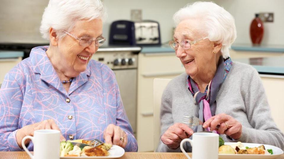 Two senior women eating at a table