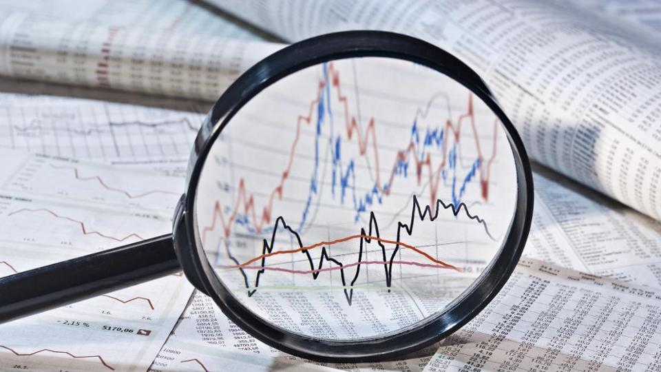 Newspapers and documents with numerical series and graphics enlarged by a magnifying glass 