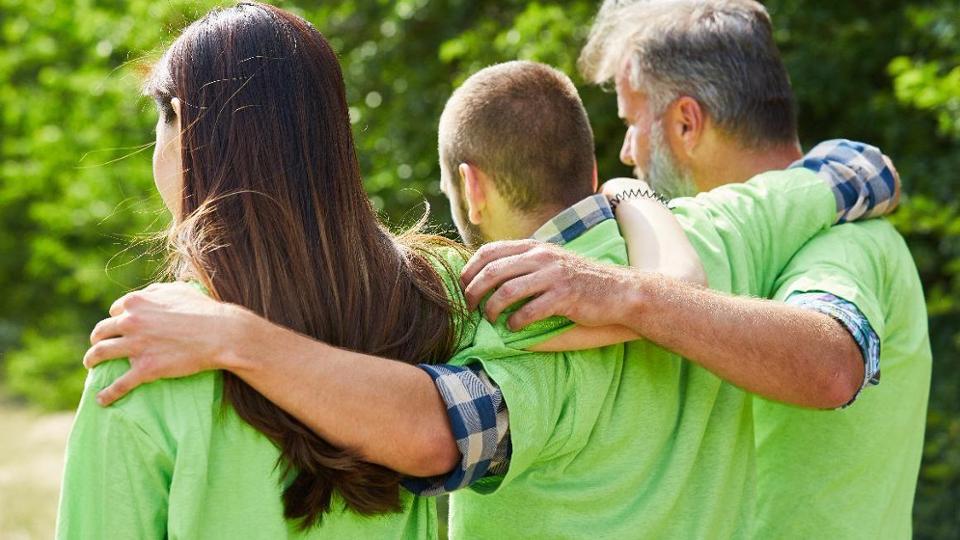 Three people grab each other by the shoulders.